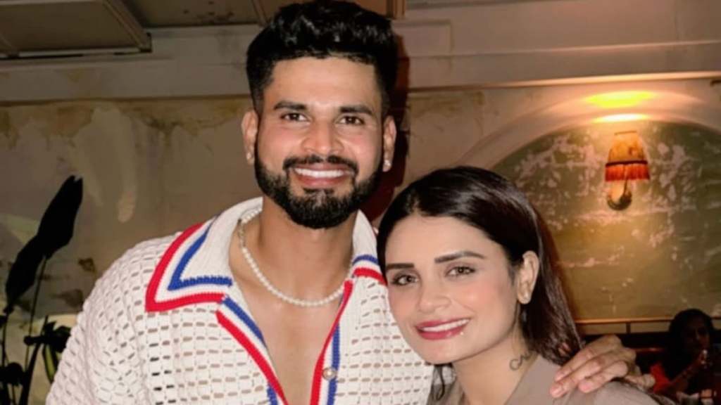 Shresta Iyer poses with a smiling Shreyas Iyer in a warmly lit restaurant setting.