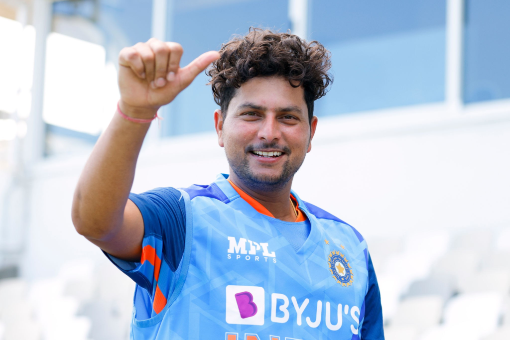 Kuldeep Yadav smiling and giving a thumbs-up while wearing the Indian cricket team training jersey during a practice session.